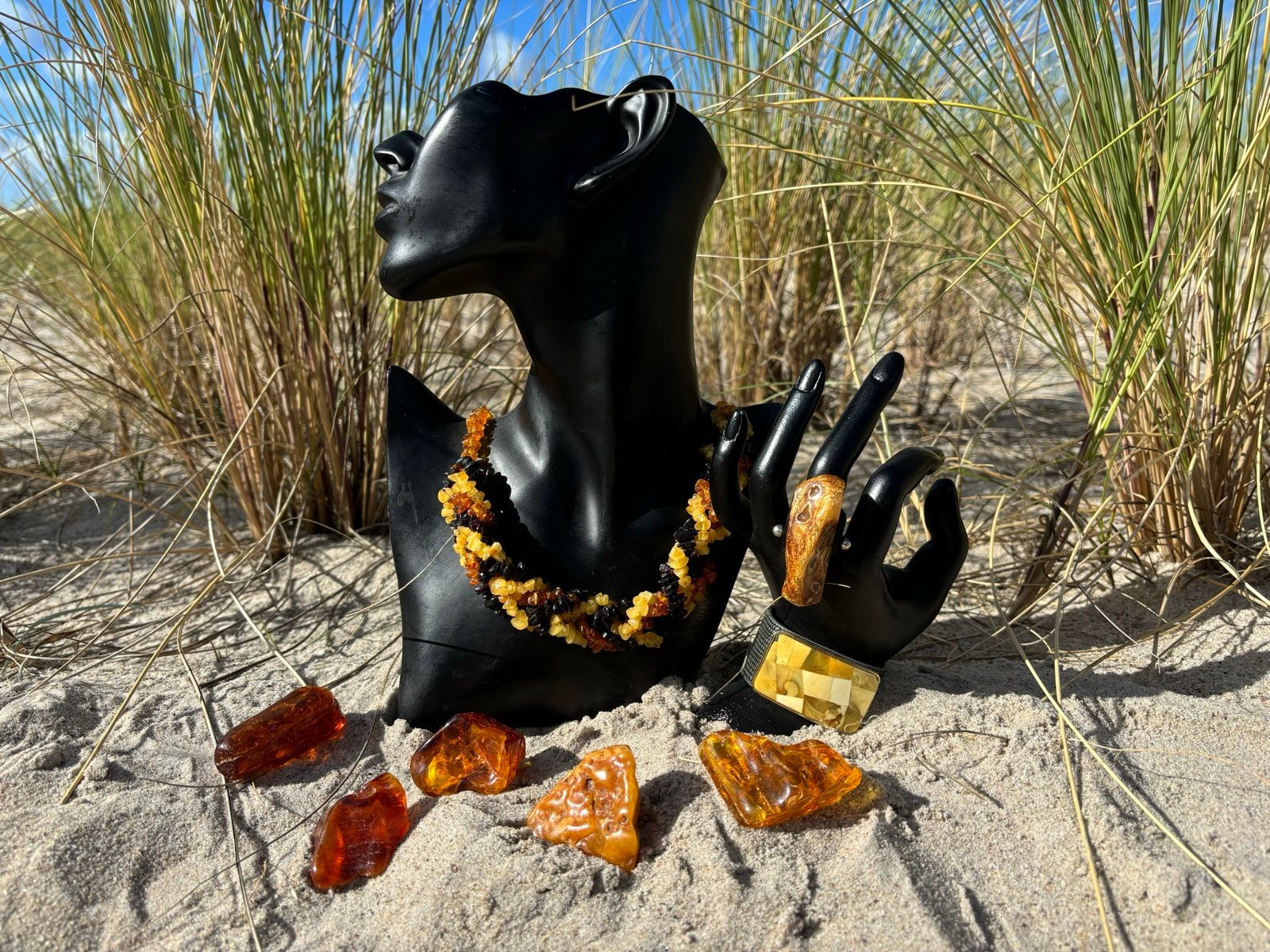 Bernsteinkette und Bernsteinschmuck auf einer Büste am Strand
