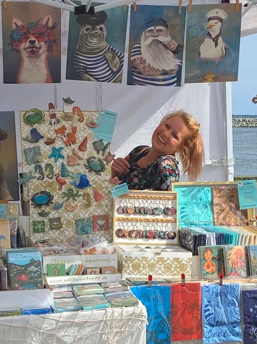 Kunsthandwerkerin an ihrem Stand mit Bildern und Keramik in Boltenhagen